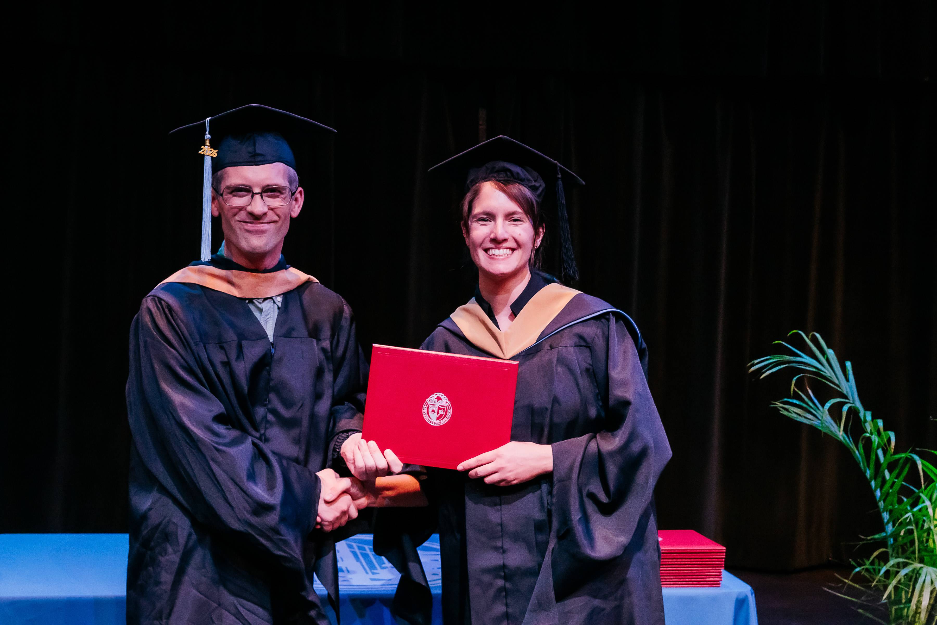 a person and person in graduation gowns holding a red certificate